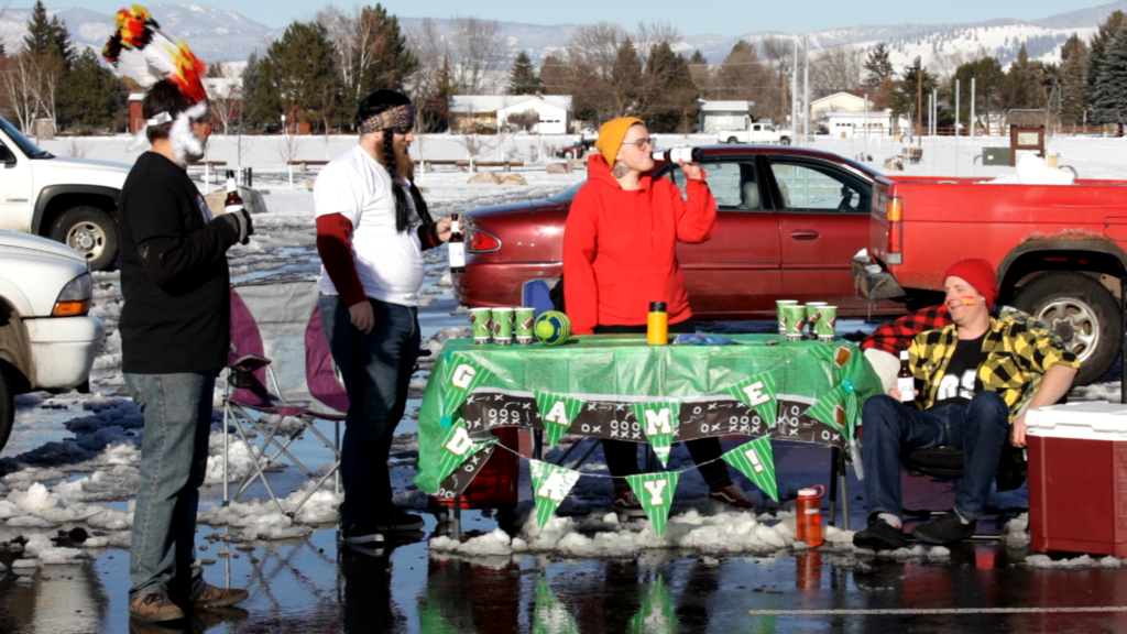 Four men stand by a table in a parking lot in the winter time.