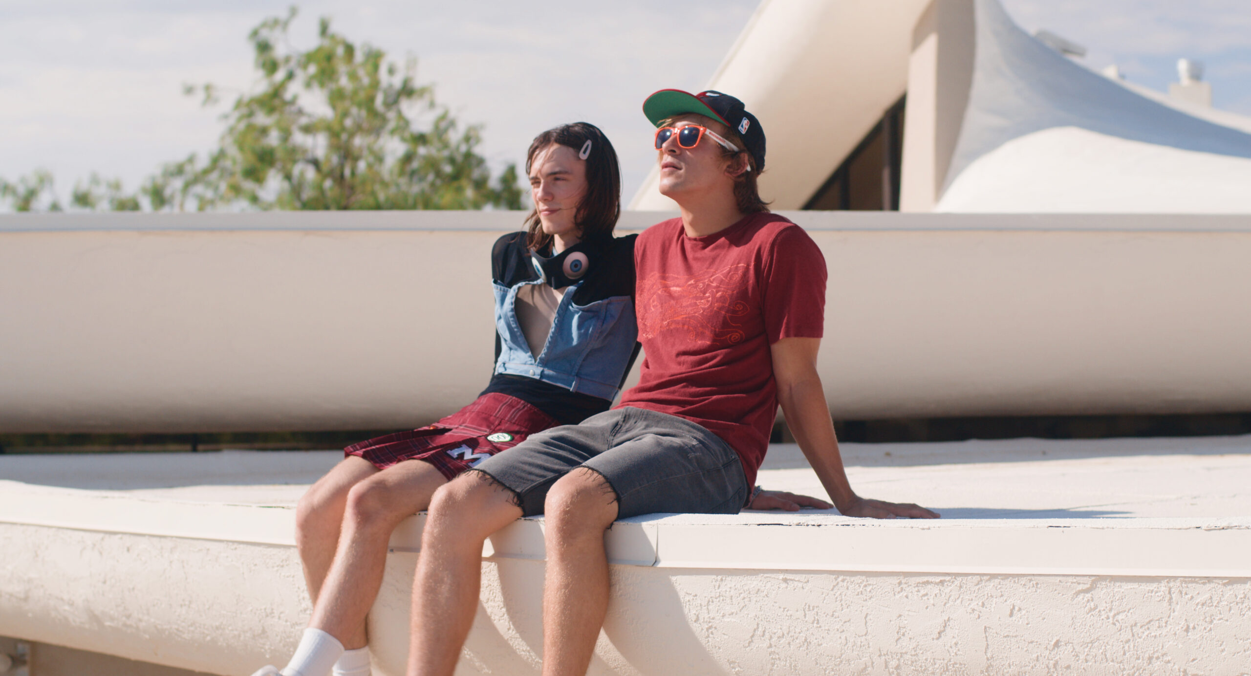 Two people sit next to each other outside on a white surface