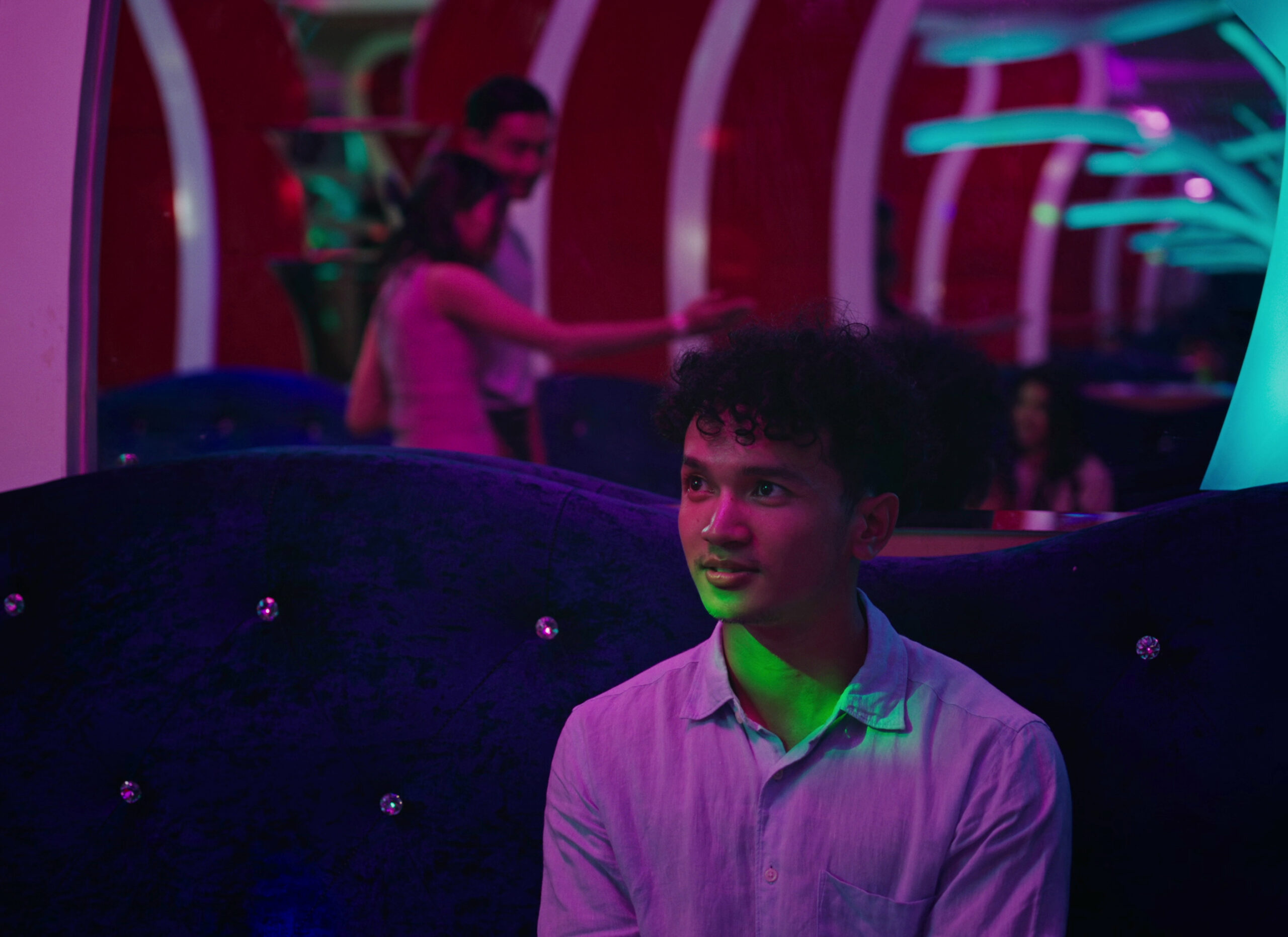 Person sits inside on couch with multicolored lights around them.