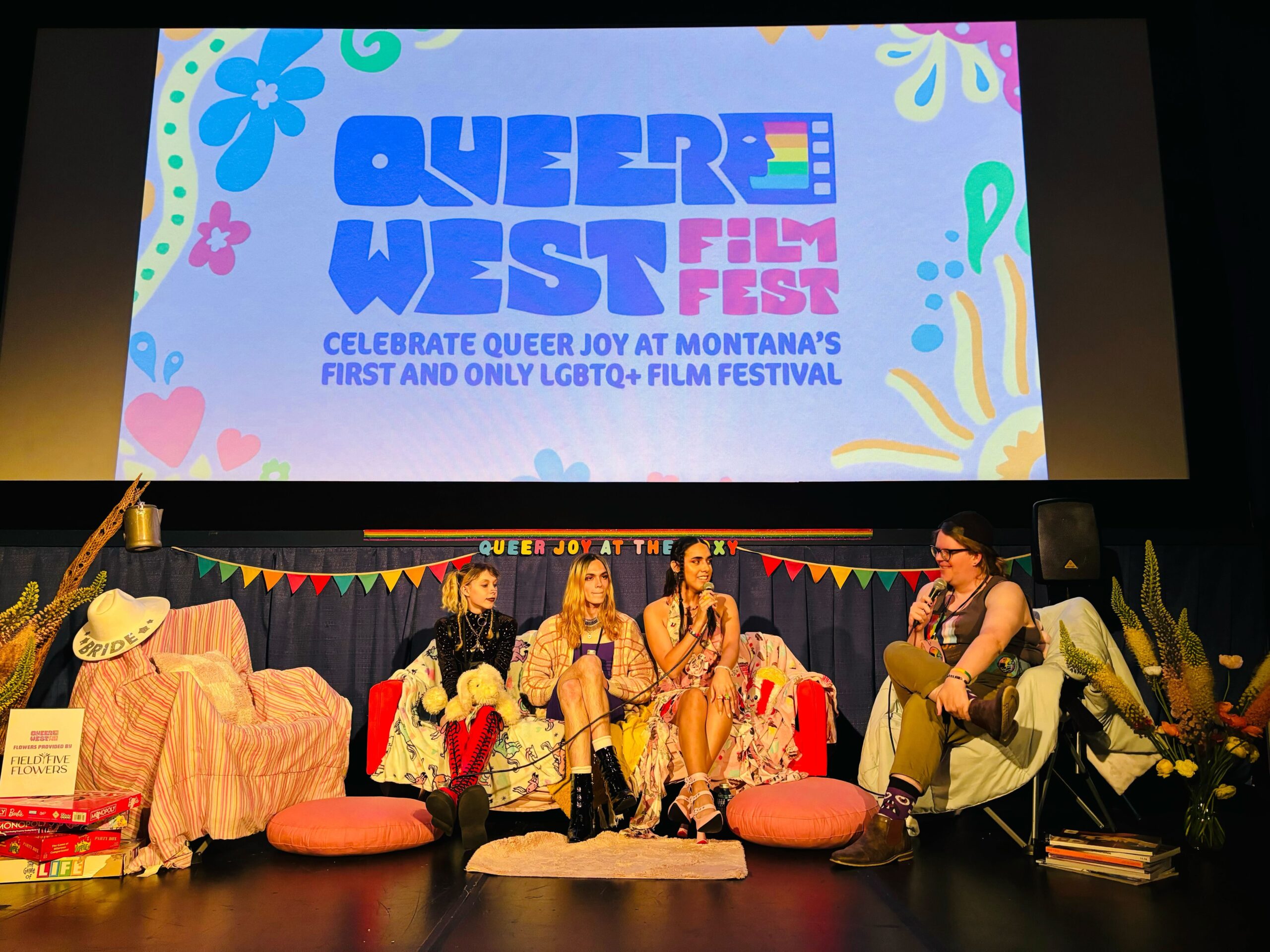 qwff-talkback Group sits on movie theater stage talking with mics.