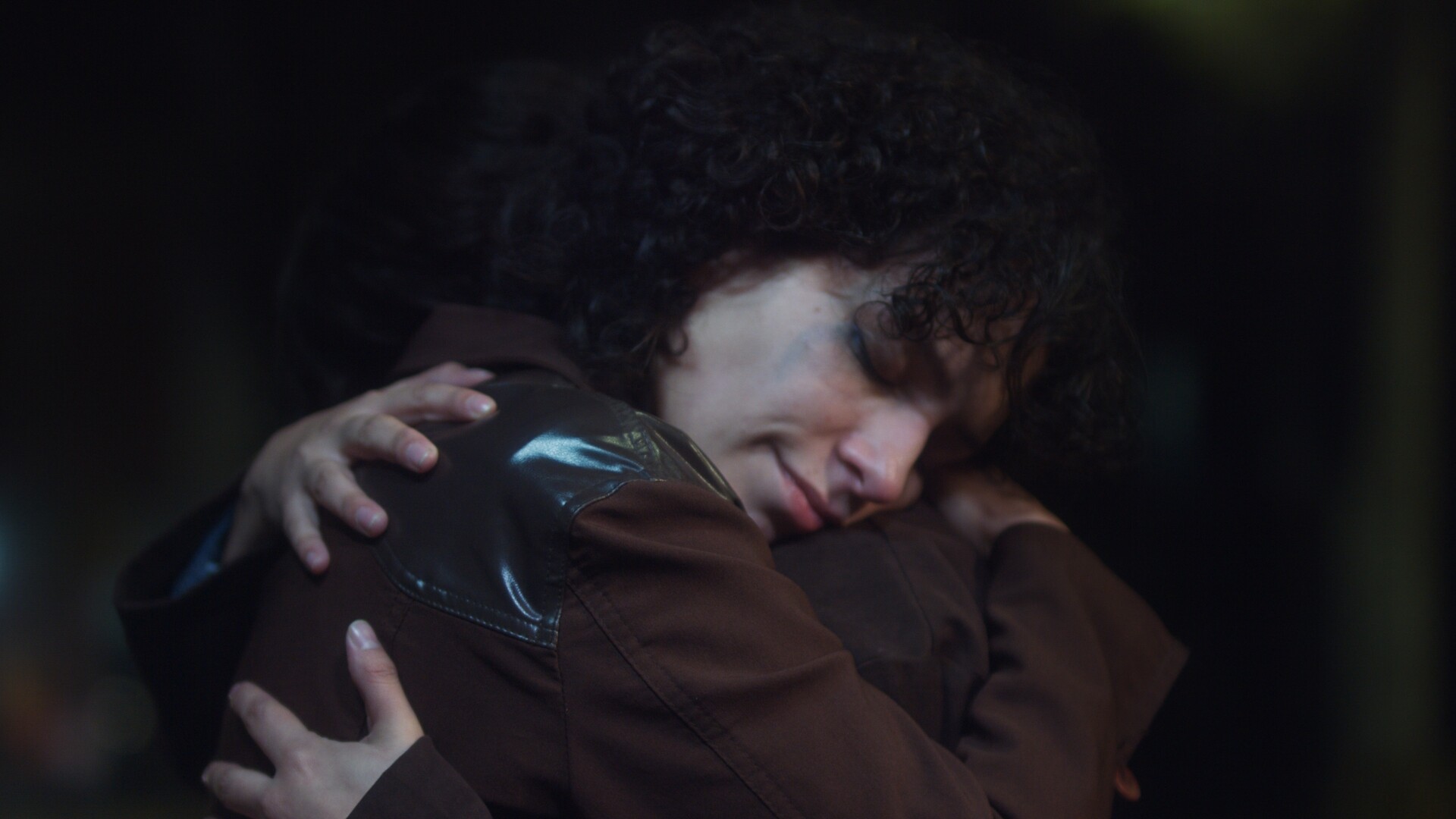 Two people embrace in low light setting.