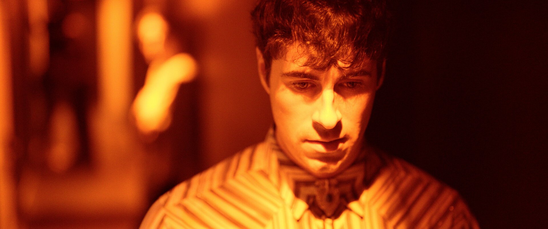 Person in yellow light looks down.