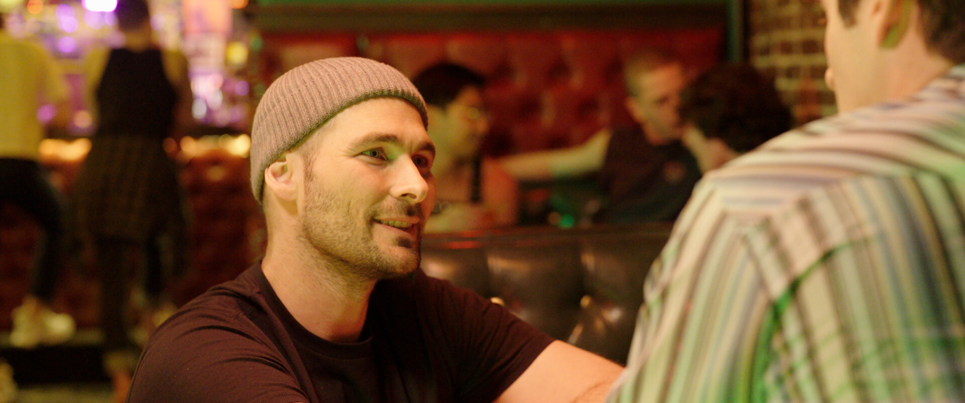 Person wearing hat in bar setting looks right.