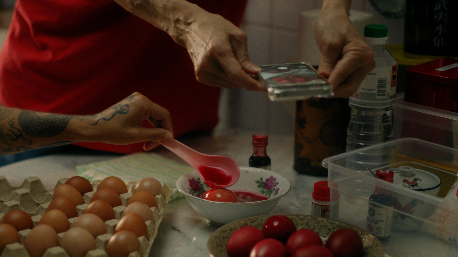 Peoples hands dying eggs red.