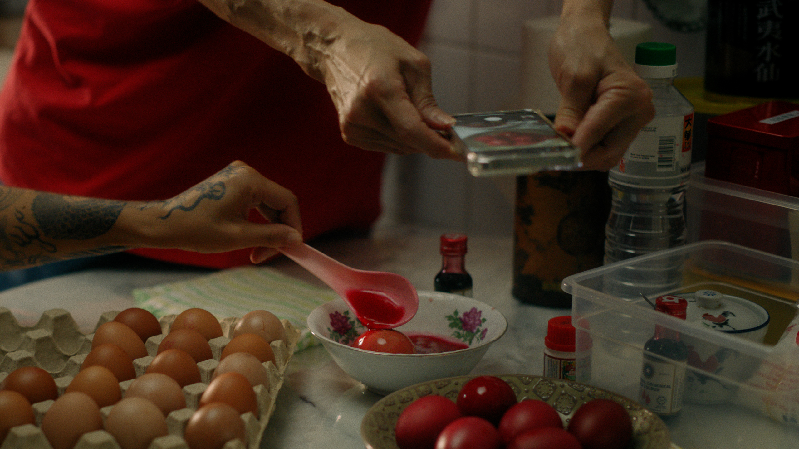 Peoples hands dying eggs red.