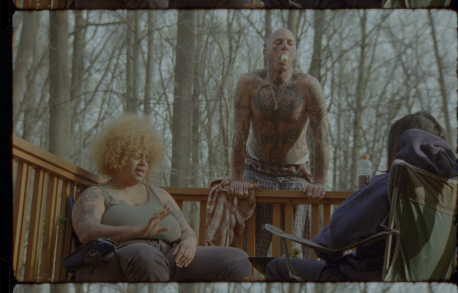 Three people sit are in forest setting interacting.
