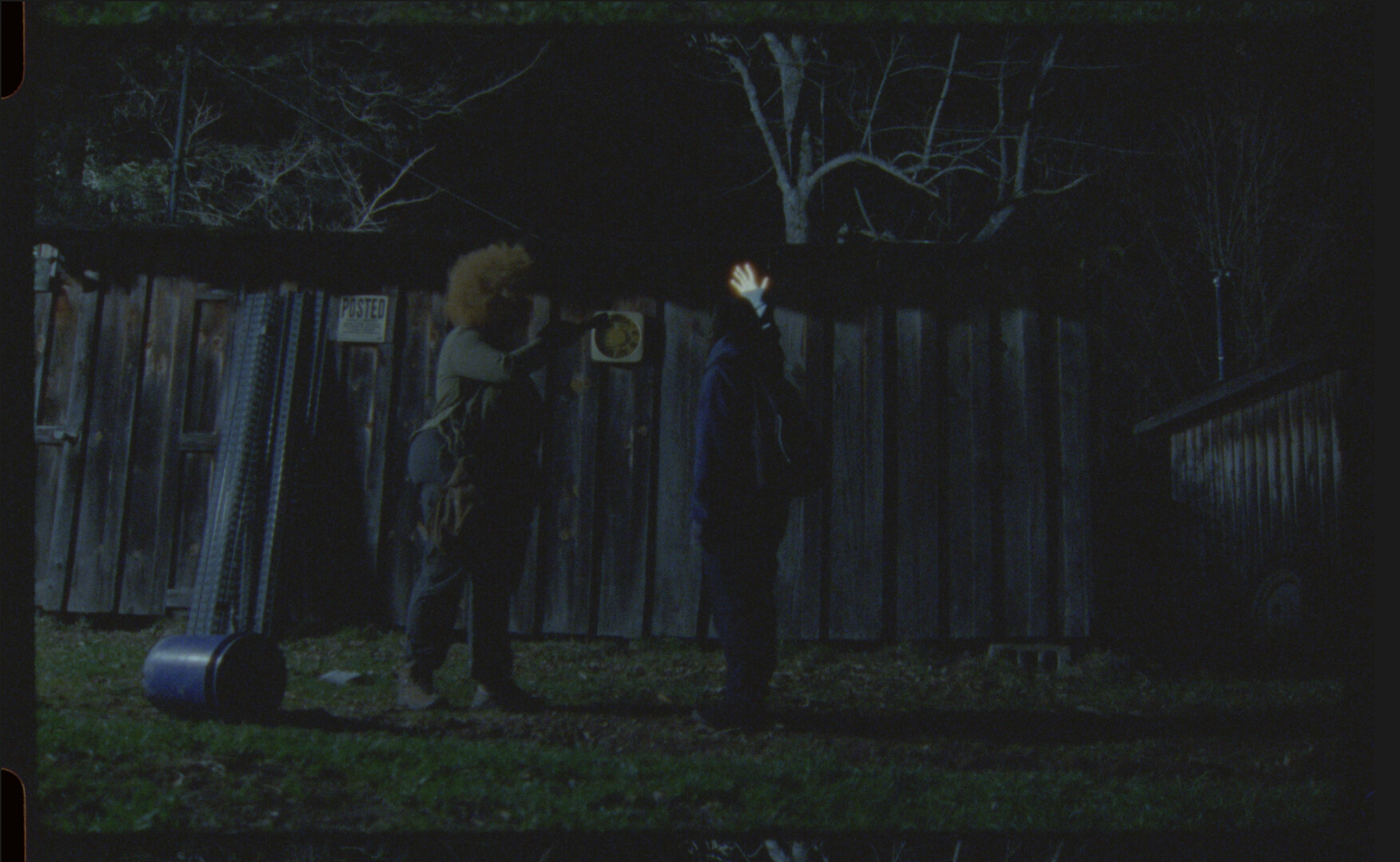 Two people face each other in low light.