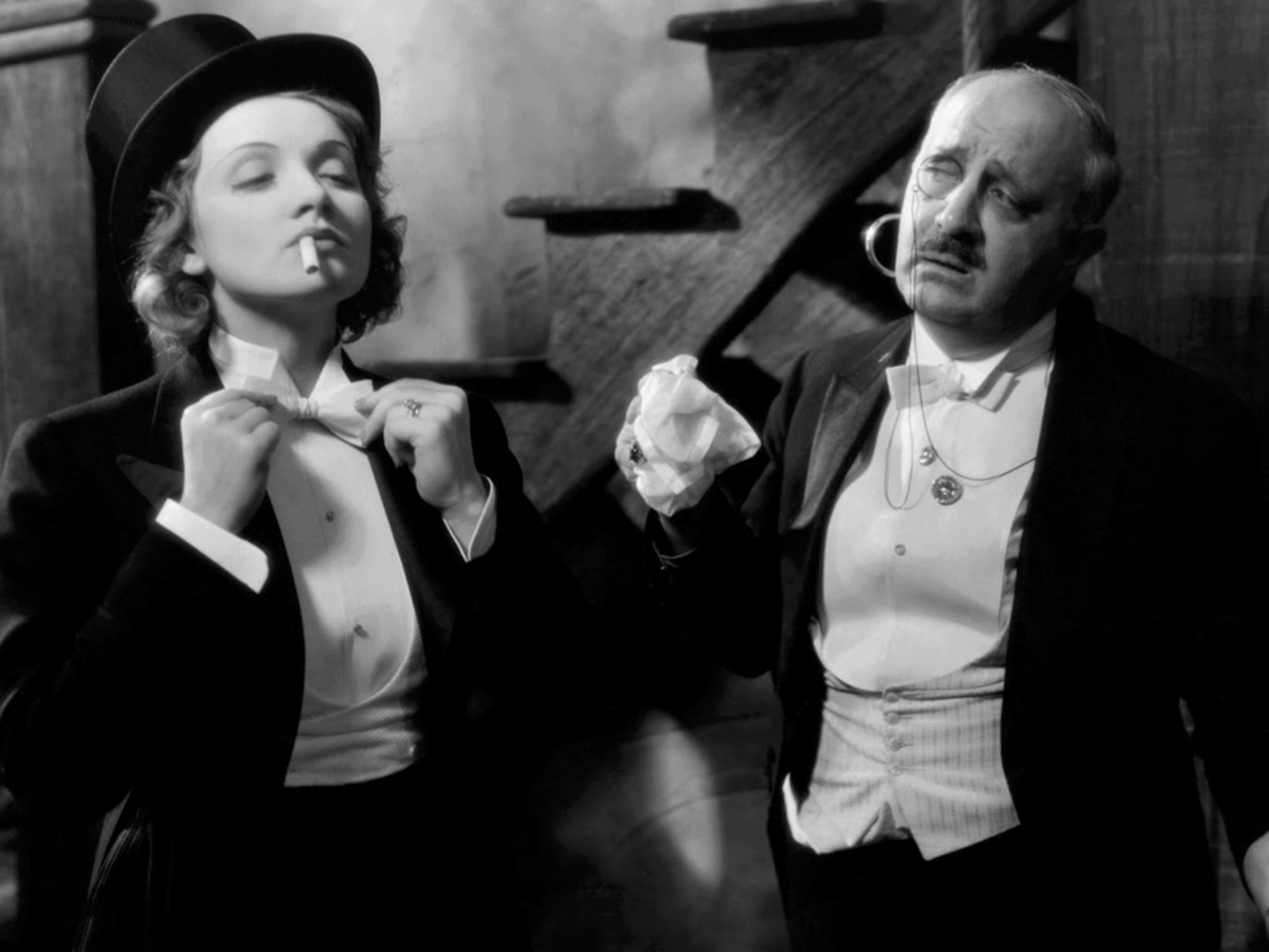 Greyscale image of two people in tuxedos.