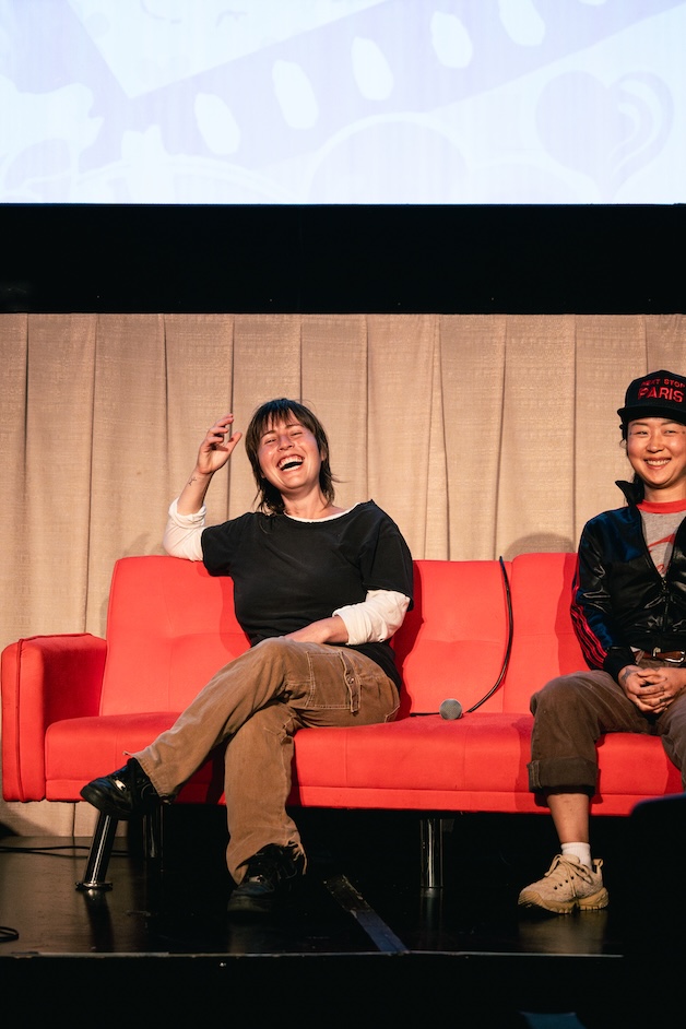 People smiling during Q&A on stage for Queer West Film Festival.